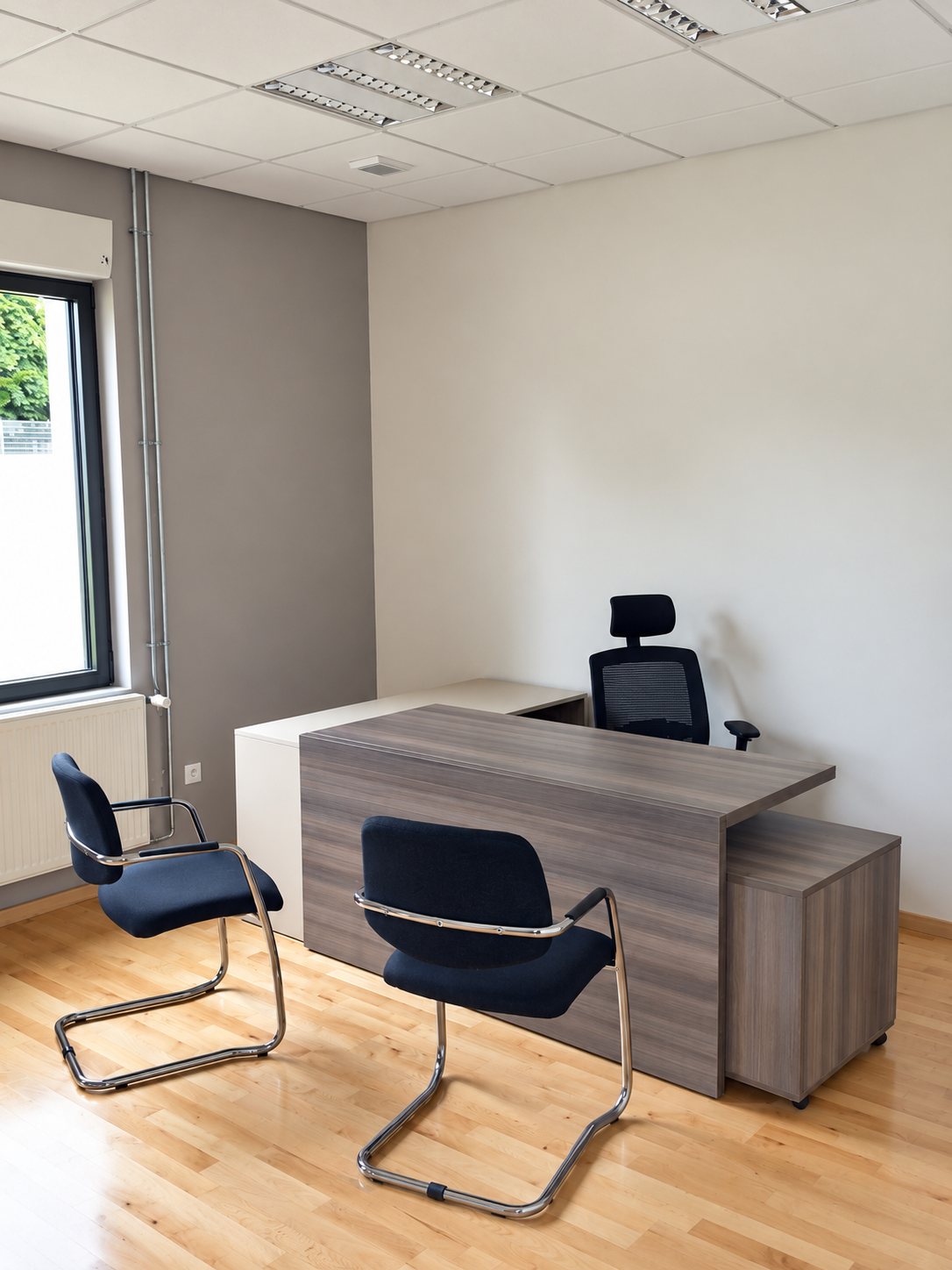 Un bureau moderne équipé d'un bureau en bois gris, d'un fauteuil de direction noir et de deux chaises visiteurs bleu foncé sur un parquet clair.